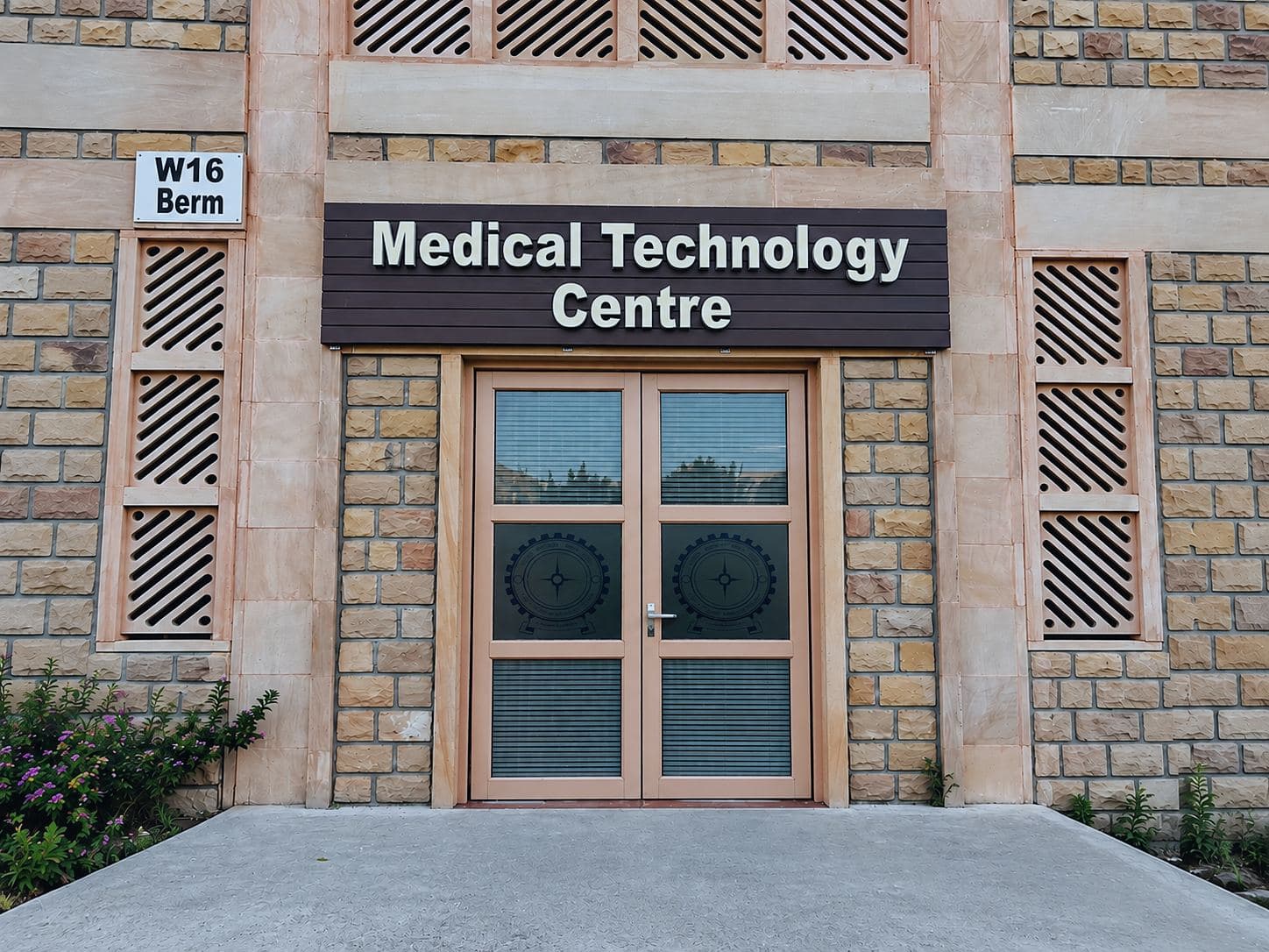 Entrance of the Medical Technology Centre building at IIT Jodhpur: sandstone façade, signage above double doors, and a 'W16 Berm' location board