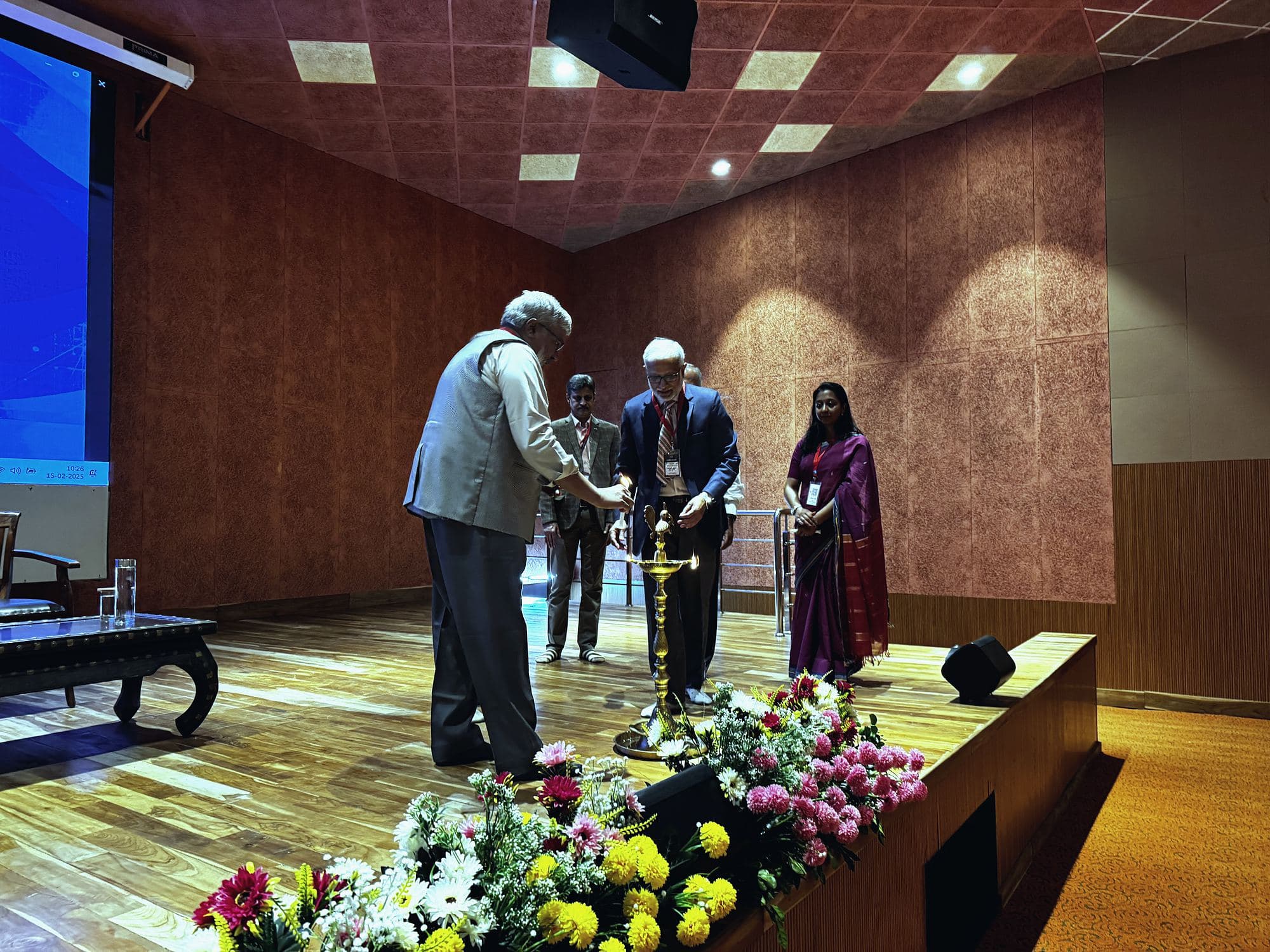 Dignitaries on stage beside a floral arrangement during the conference inauguration