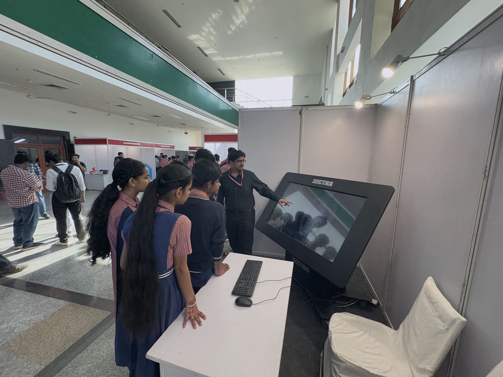 Young visitors trying a touchscreen demonstration at an exhibition stall